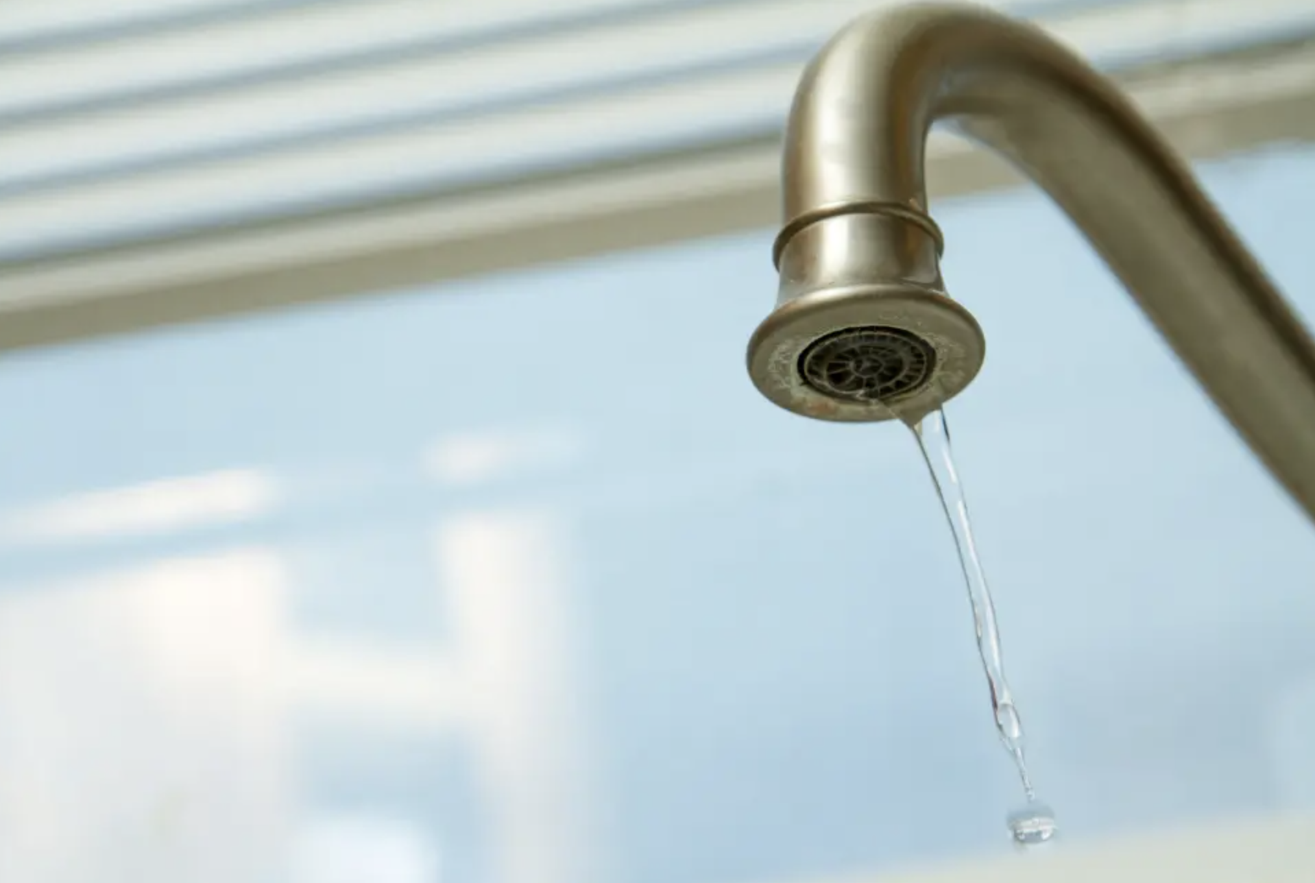 Close-up of a leaking kitchen faucet with water dripping